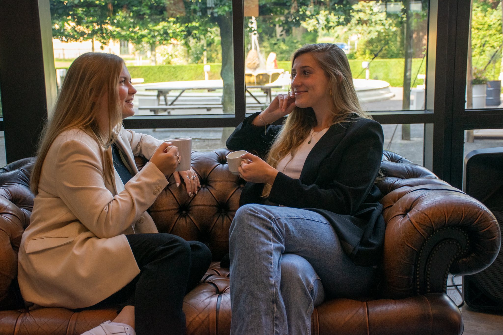 twee vrouwen praten op bank met koffie